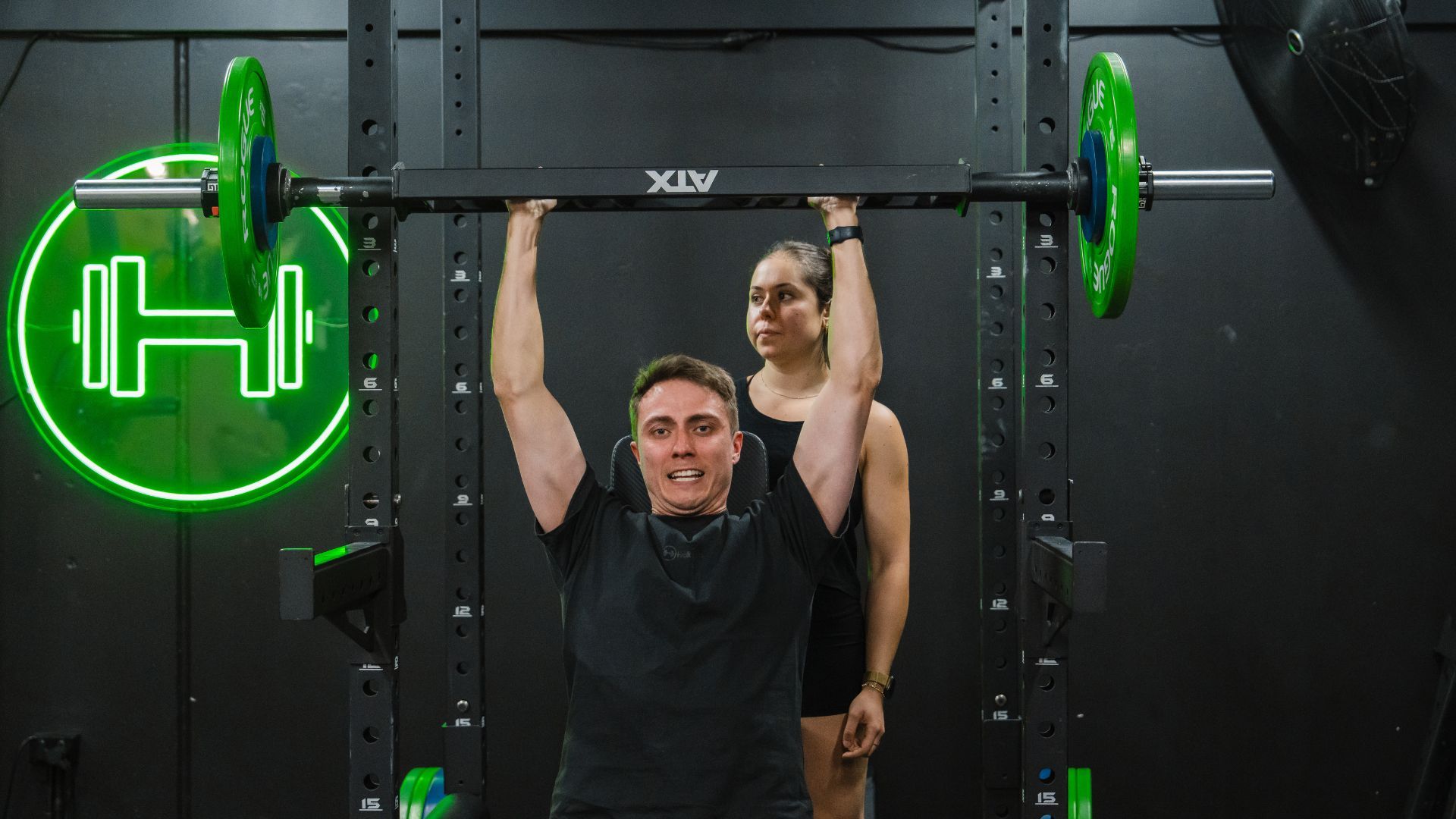 Personal trainer coaching a client in the gym, helping him with form and technique.