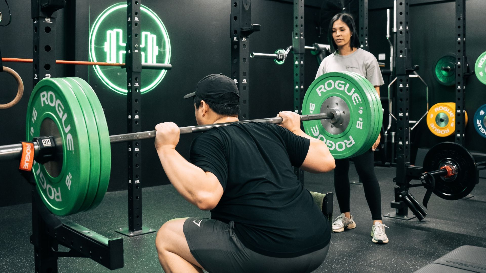 Client doing a barbell squat with coach's guidance at Habitat Gym