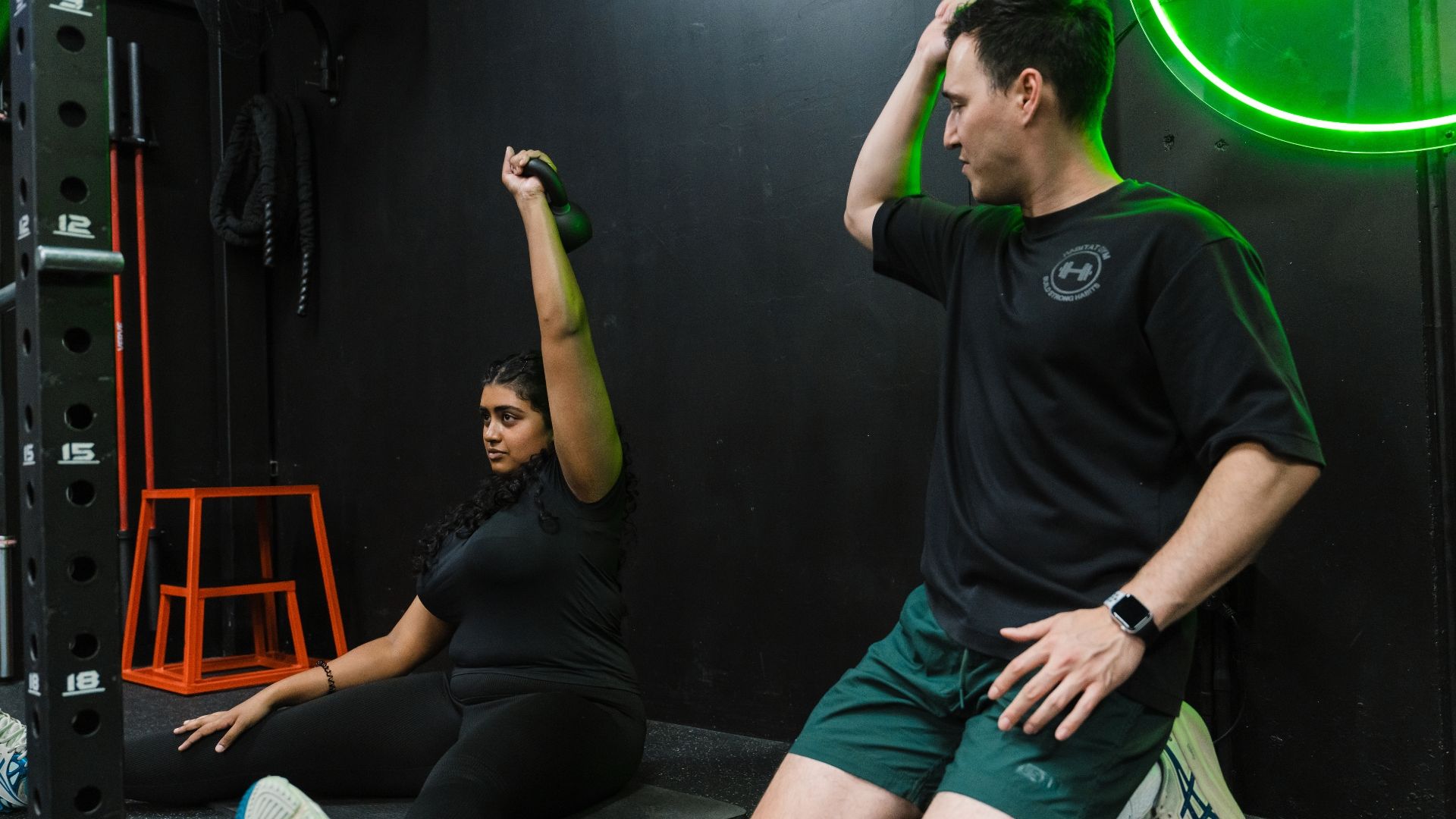 Personal trainer coaching a client in the gym, helping him with form and technique.