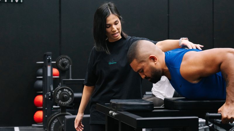 Coach at Habitat Gym in Prestons guiding a client through a modified lift while training around an injury