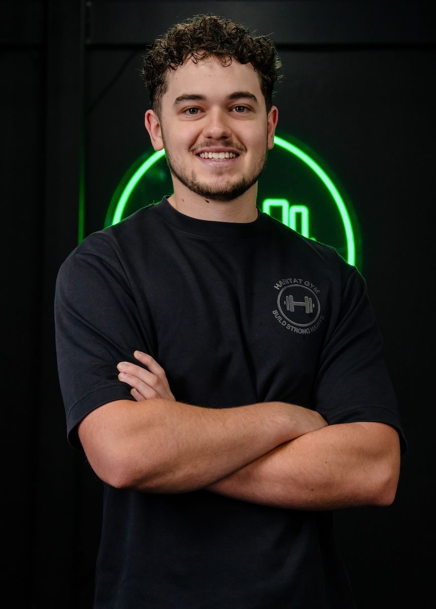 Jayden, coach and Exercise Scientist smiling inside Habitat Gym