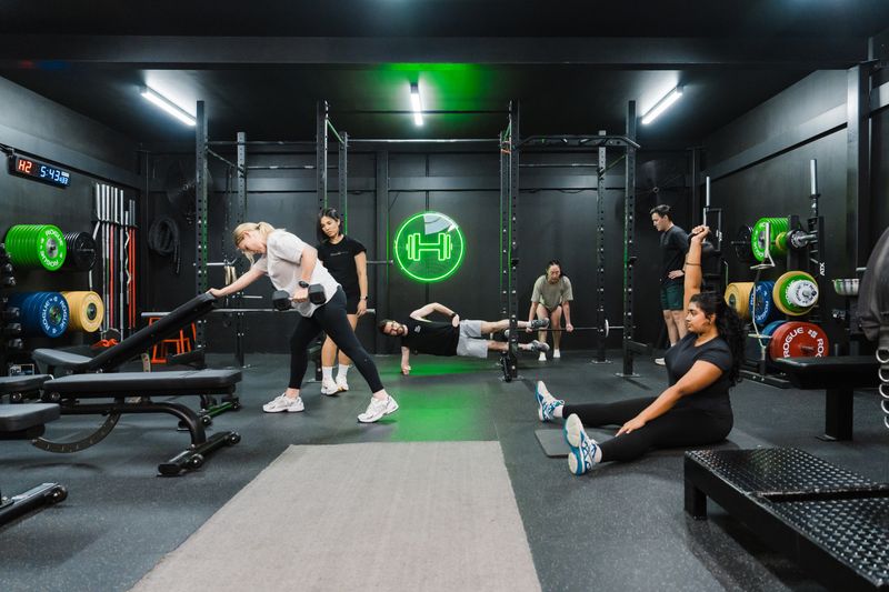 Semi-private personal training session at Habitat Gym with coach supervision, members performing strength exercises in a structured gym environment.