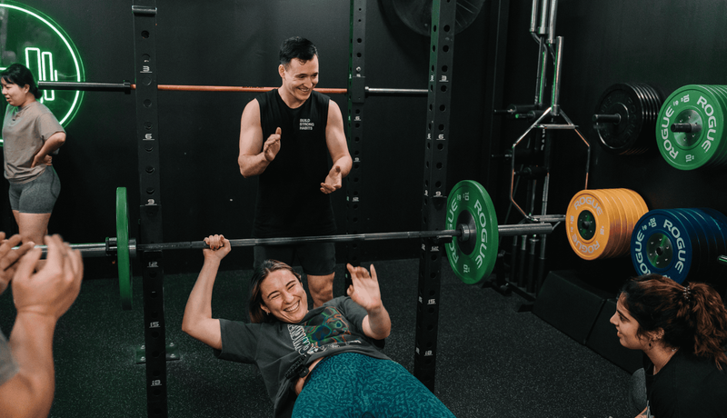 Member having fun whilst bench pressing inside Habitat Gym’s private training facility in Prestons