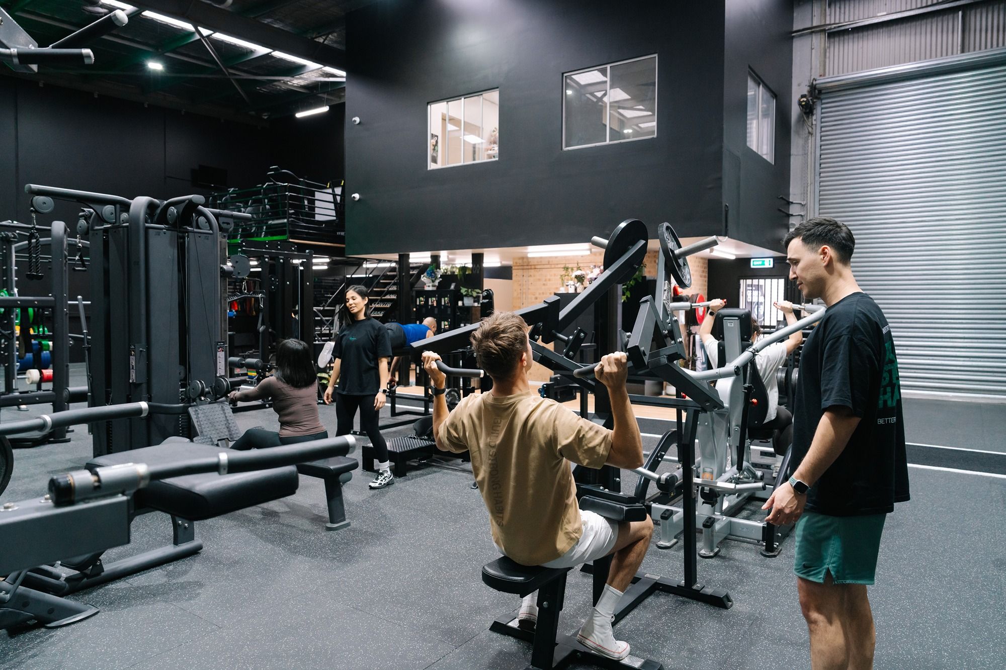Group training session at Habitat Gym with members and a coach working through strength and conditioning exercises on gym equipment.