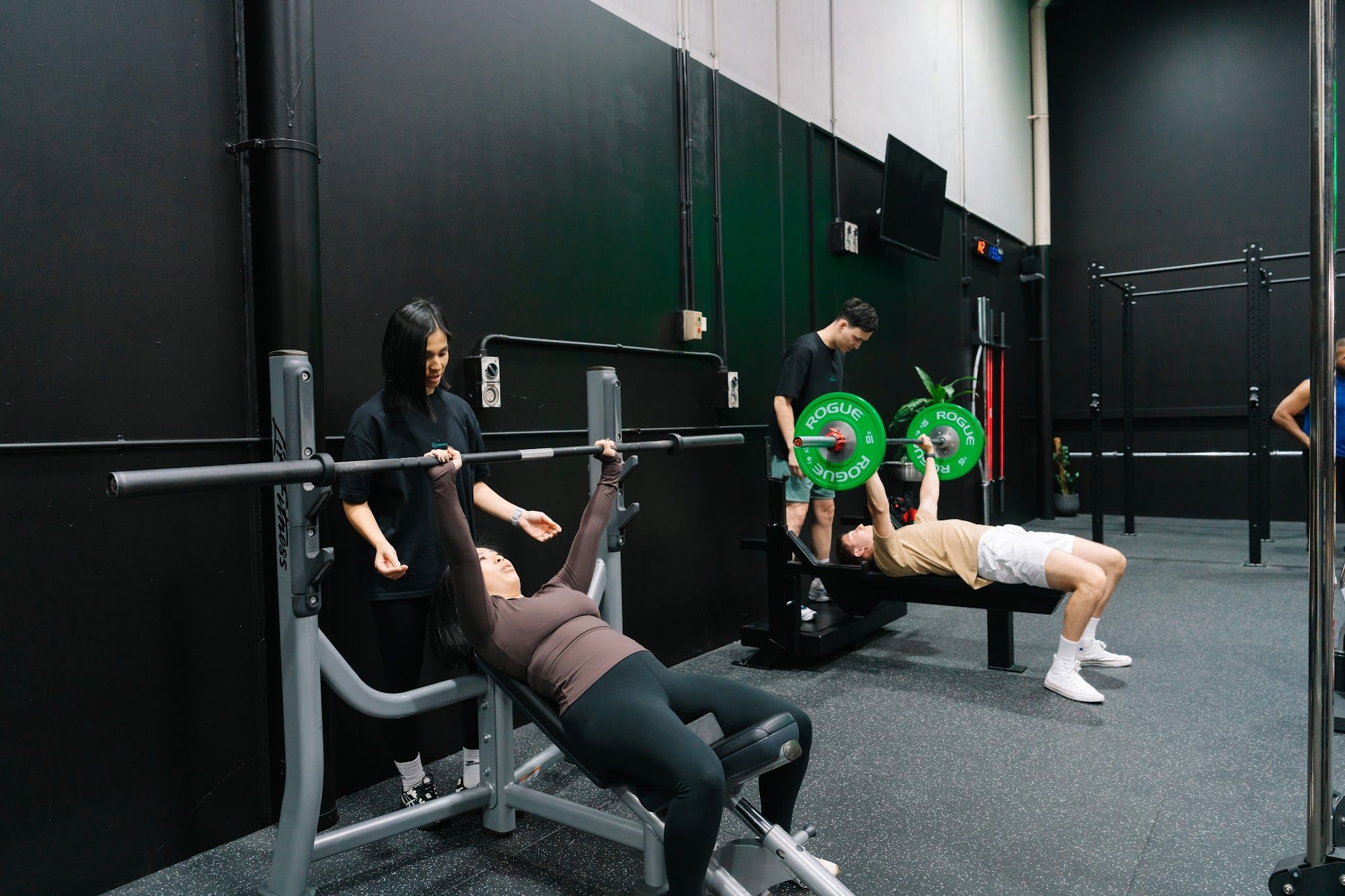 Coach guiding a member through a bench press in Habitat Gym's private gym in Prestons