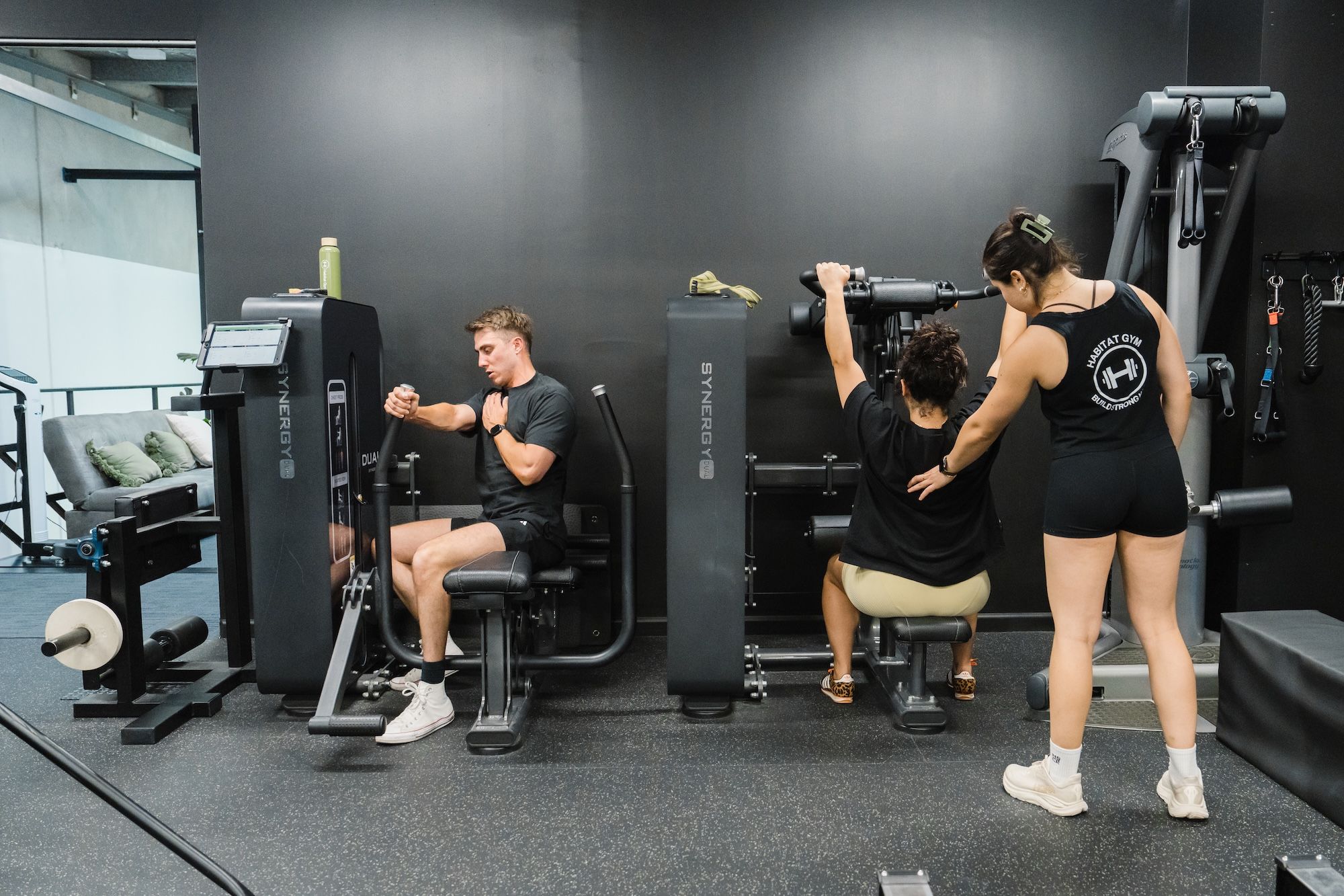Clients training on Synergy resistance machines while a coach supervises at Habitat Gym in Prestons