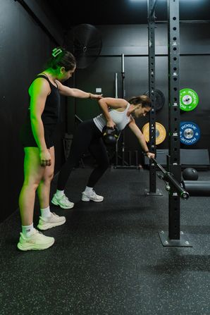 Coach Isabelle guiding a client through a single-arm kettlebell row at Habitat Gym in Prestons