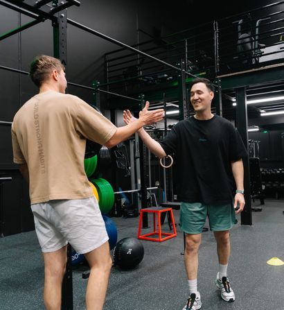 Coach and member sharing a laugh and a high-five between sets at Habitat Gym in Western Sydney