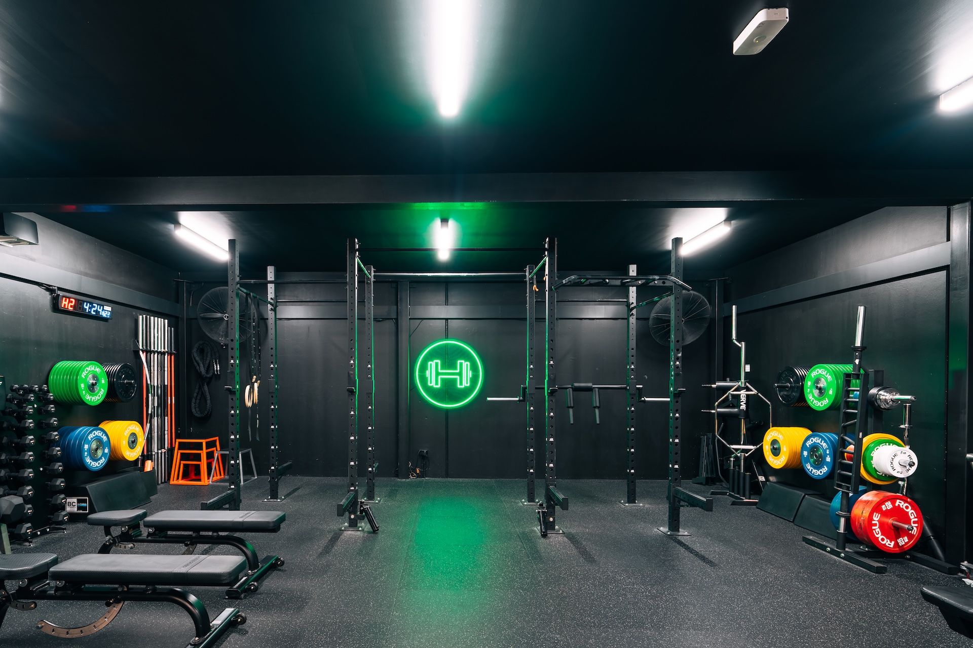 Front wide angle view of strength training zone in Prestons Gym featuring a neon logo sign of Habitat's logo