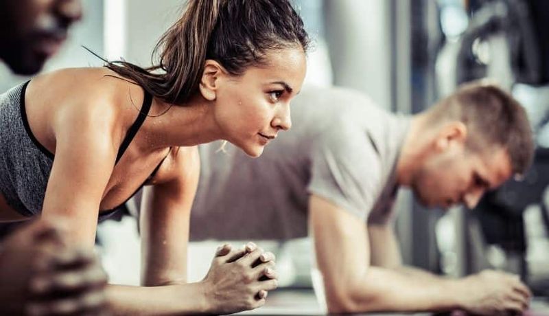 Gym members holding a strong plank position on the gym floor