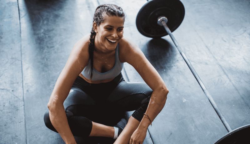Smiling woman on gym floor mid-workout enjoying her fitness routine