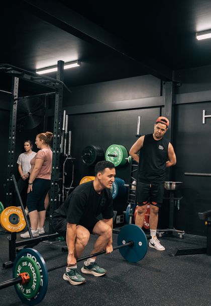 Coach Ben demonstrating deadlift with Rogue bumper plates to client inside their Prestons gym