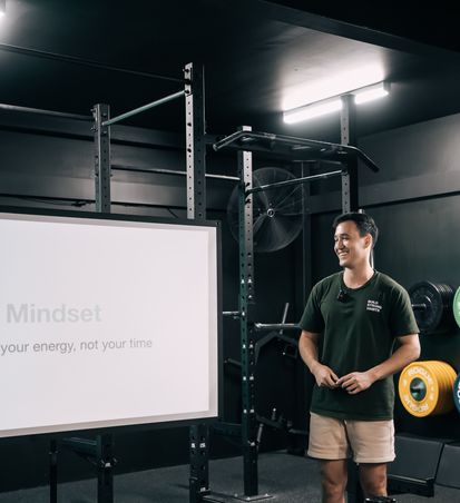 Coach Ben standing in front of the white screen, and presenting during a workshop at Habitat Gym