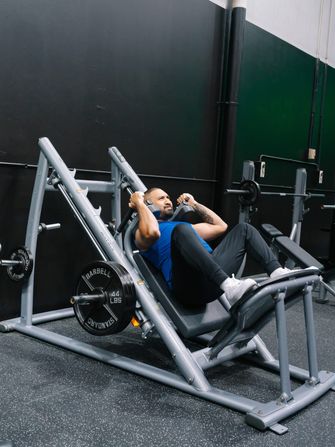 Member pressing out reps on the 45-degree hack squat machine loaded with iron plates
